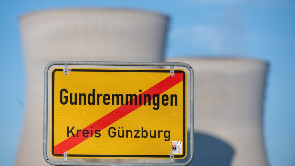Das Ortsschild von Gundremmingen, dahinter die Kühltürme. Das Kernkraftwerk im schwäbischen Gundremmingen hat im Rahmen des Atomausstiegs am 31.12.2021 seinen Betrieb eingestellt. 
