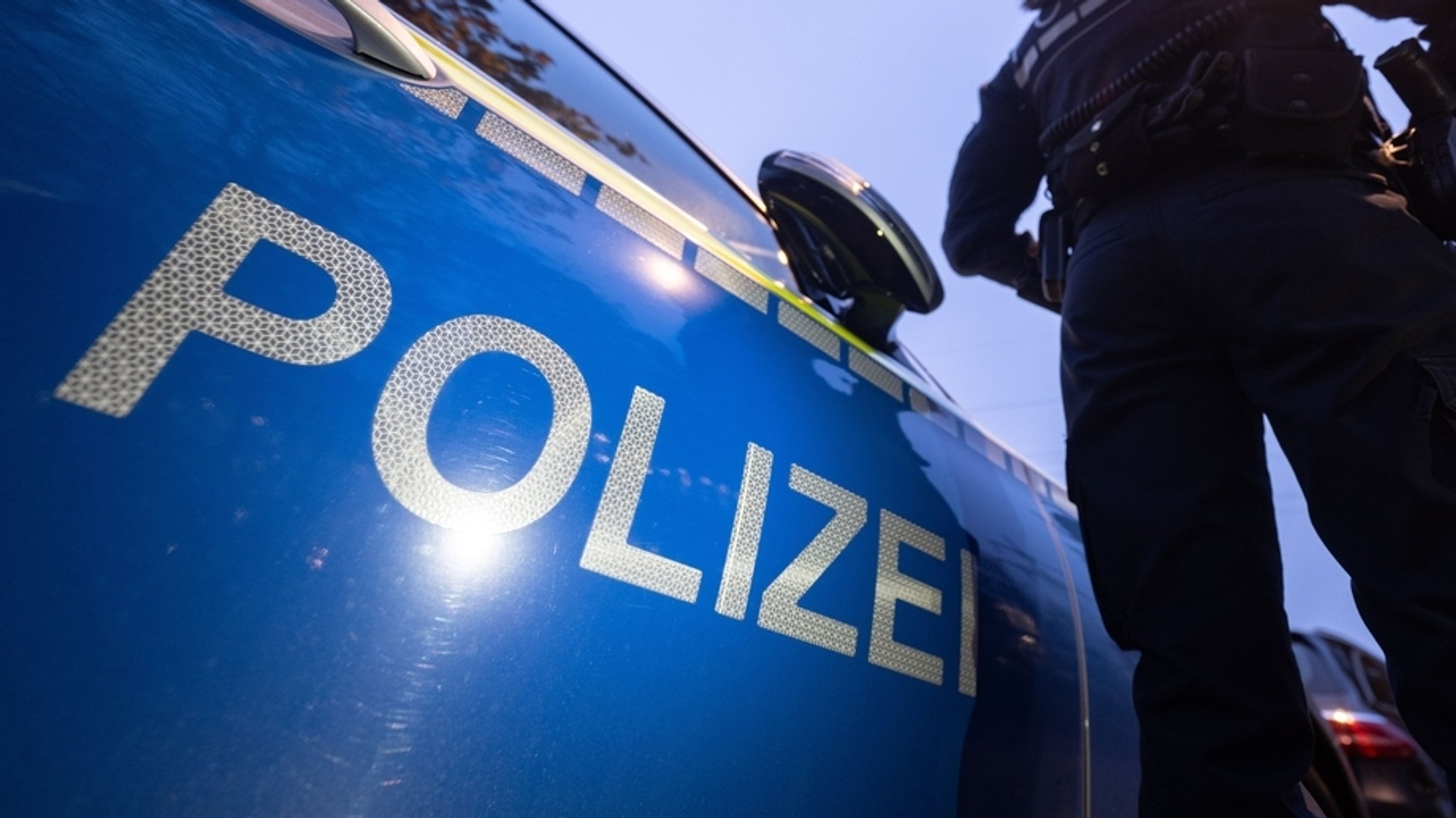 Eine Polizistin steht neben einem Polizeiauto. (Symbolbild) 