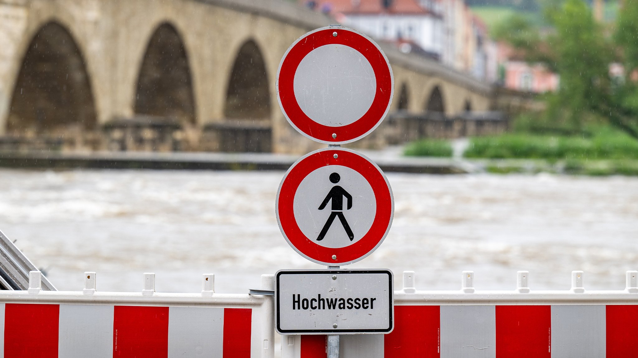 Hochwasser an einem Fluss - Ein Schild warnt davor (Archiv- und Symbolbild)