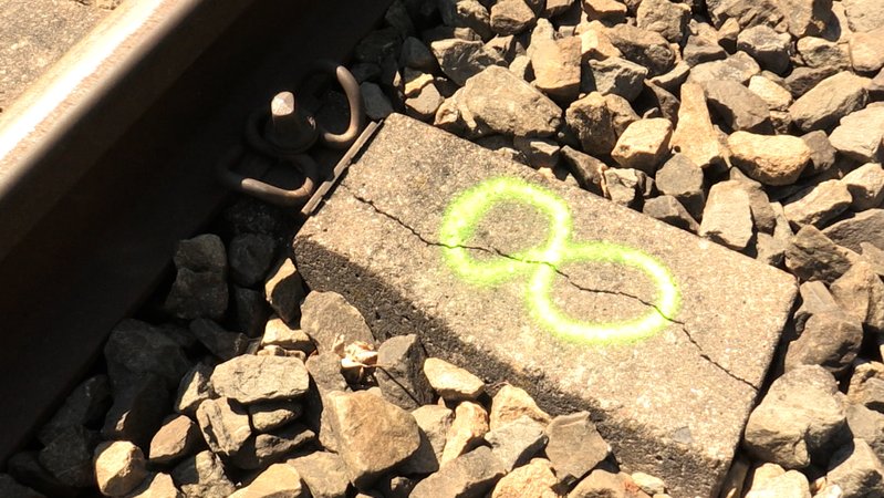 Eine gerissene Eisenbahnschwelle wurde mit Farbspray markiert | Bild: BR / Lui Knoll Eine gerissene Eisenbahnschwelle wurde mit Farbspray markiert