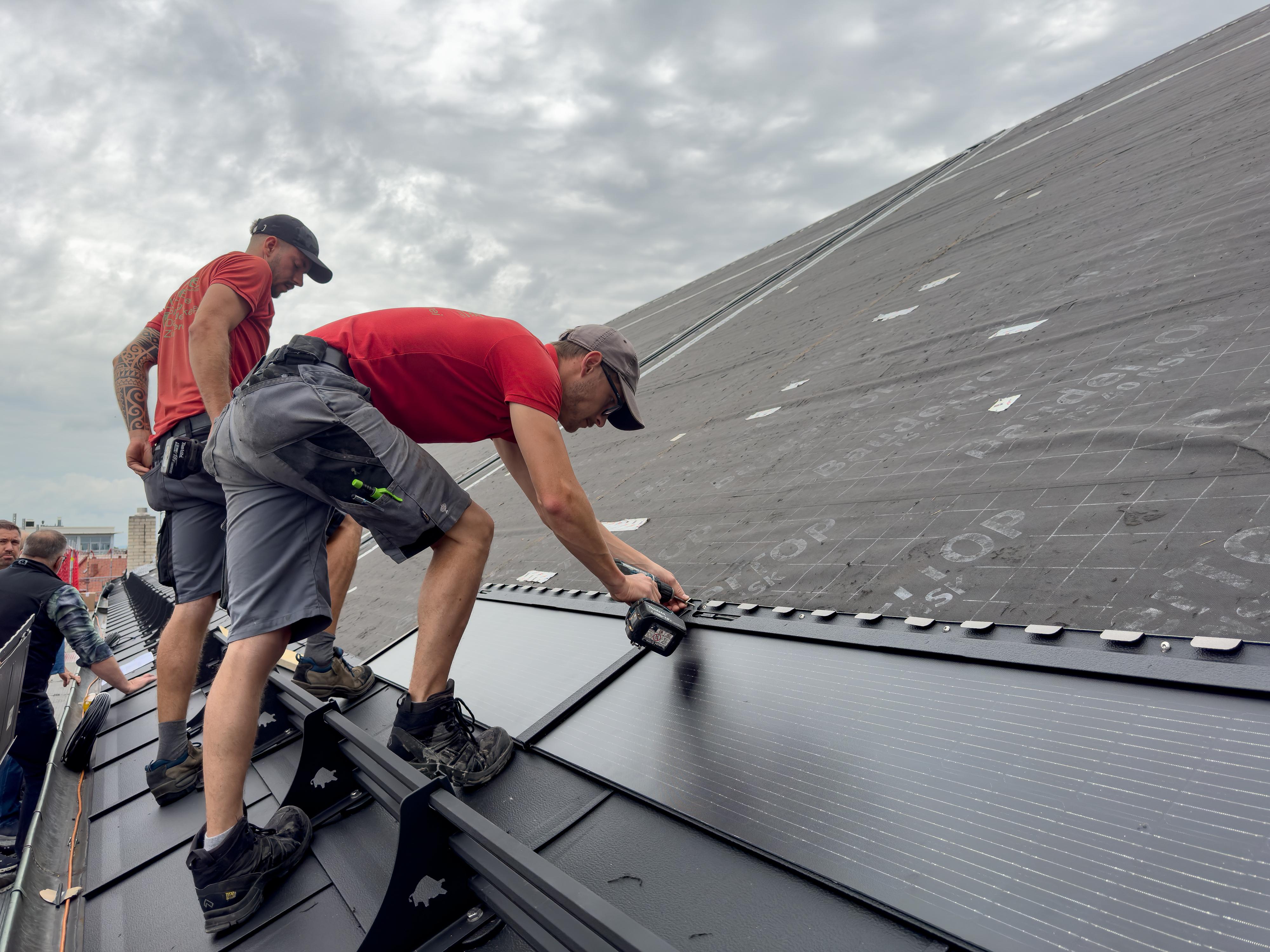 Handwerker montieren die Solarmodule auf dem Kirchendach. 