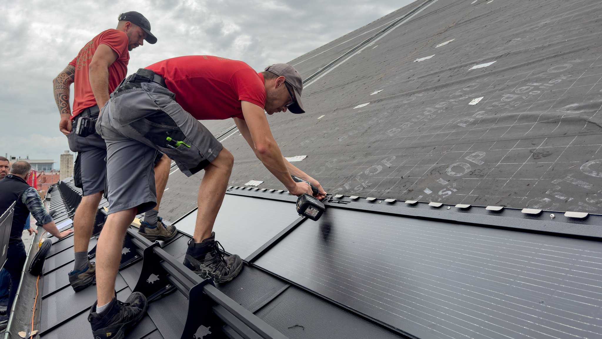 Handwerker montieren die Solarmodule auf dem Kirchendach. 