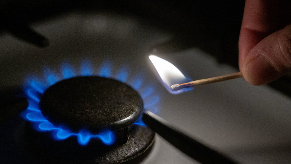 Eine Gasflamme wird auf einem Küchenherd mit einem Streichholz entzündet.
