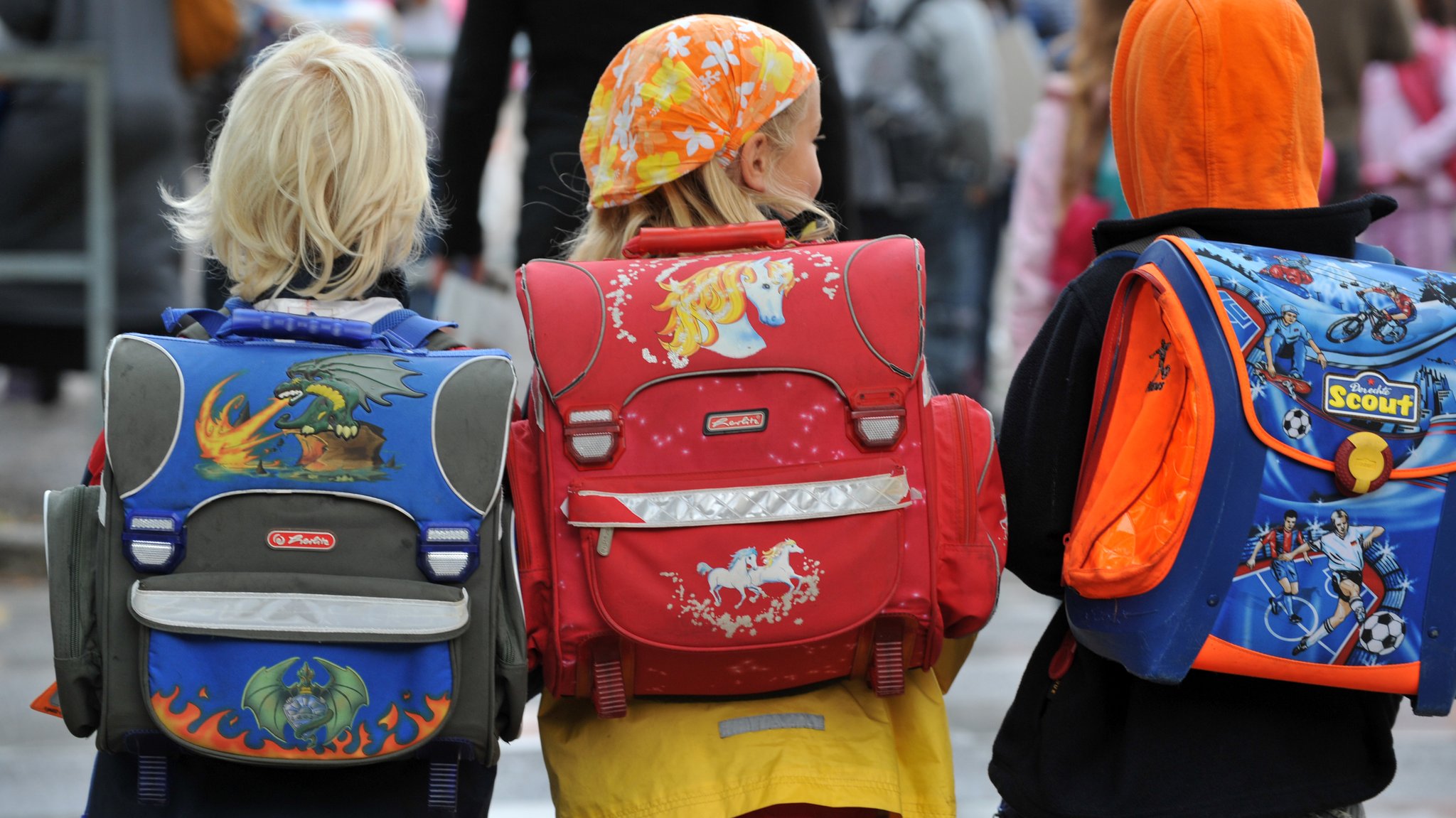 Kinder mit bunten Schulranzen auf dem Rücken.