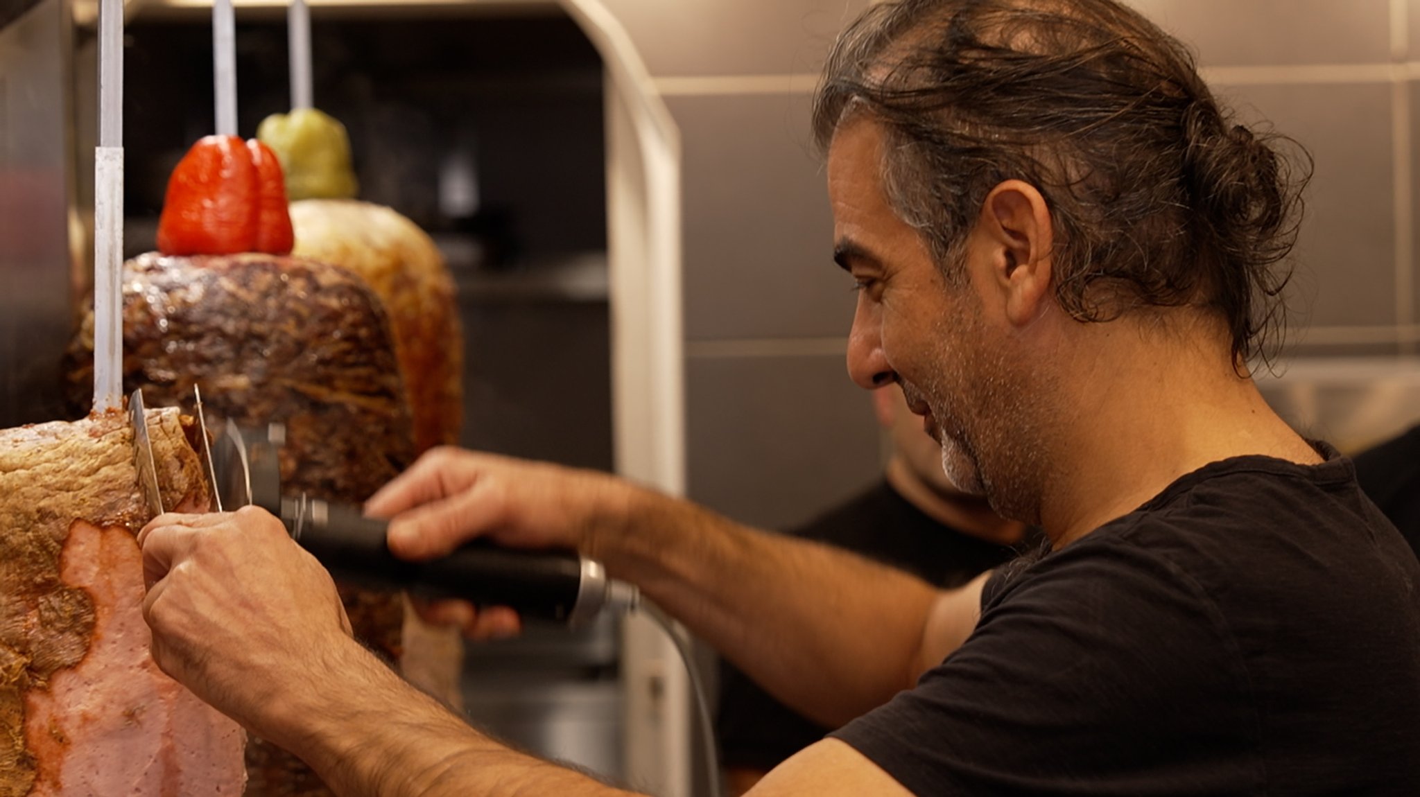 Mann schneidet Fleisch von Drehspieß