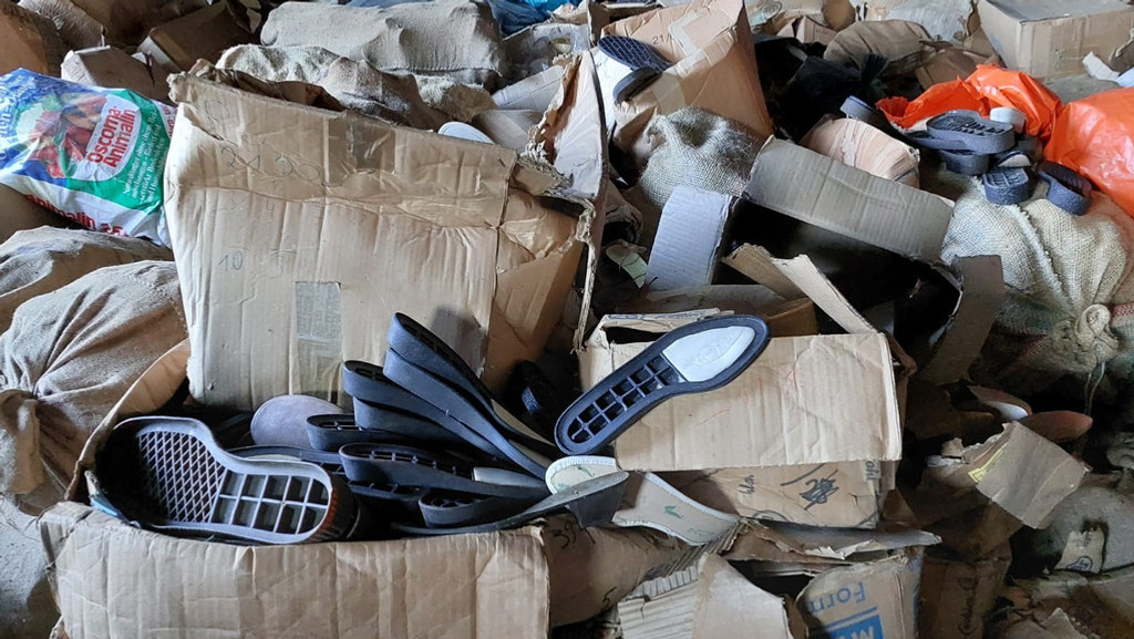 Kartons übereinander gestapelt. In einigen sind Schuhsolen zu sehen. 