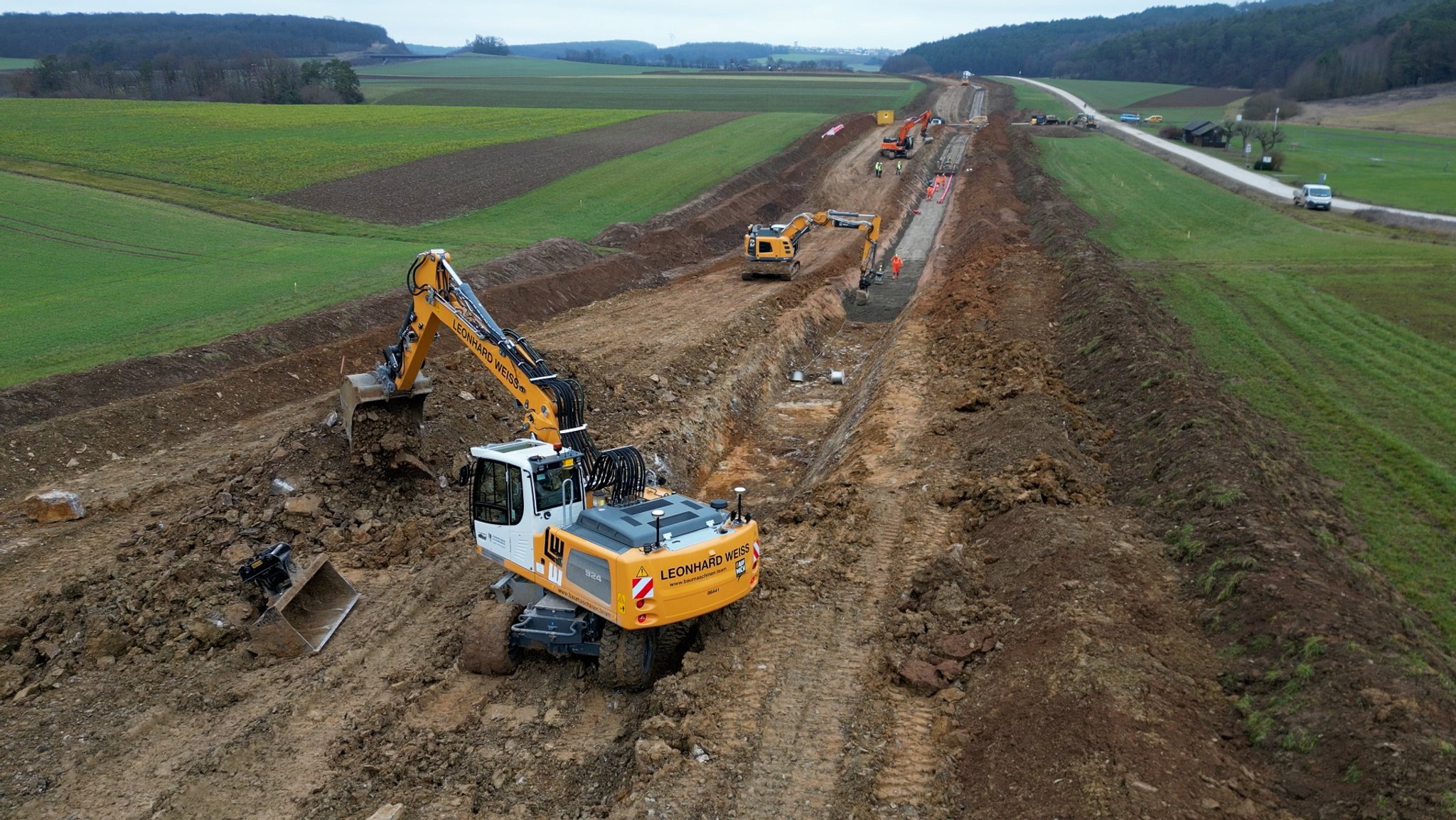 Bagger-Arbeiten: Erdkabel werden von einer Baufirma in einen breiten Kabelgraben gelegt