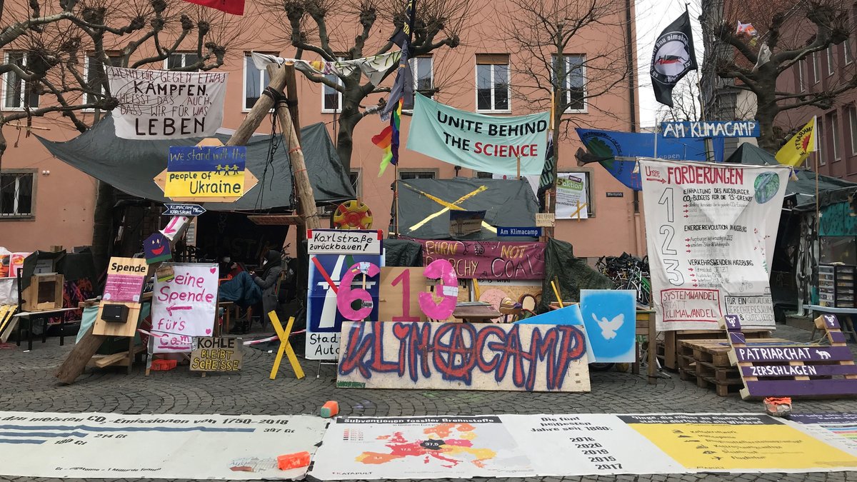 Das Klimacamp in Augsburg: Viele Transparente und ein Bretterverschlag mit Plastikfolie als Dach