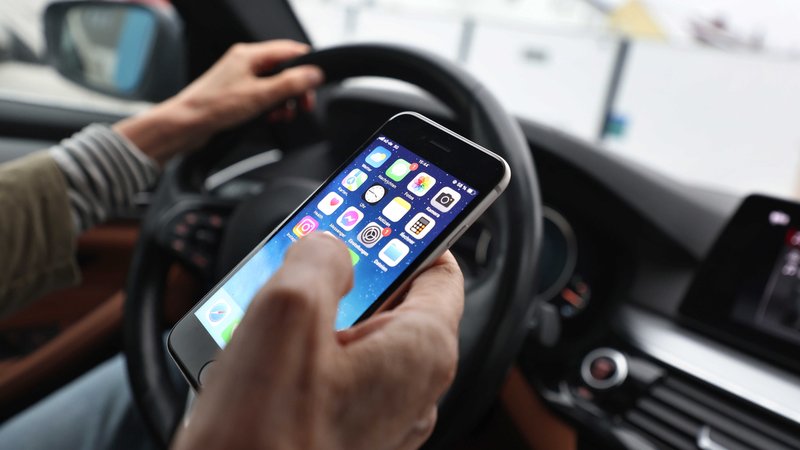 Eine Person sitzt mit einem Handy in der Hand am Steuer eines Autos. | Bild: picture alliance/dpa | Karl-Josef Hildenbrand Eine Person sitzt mit einem Handy in der Hand am Steuer eines Autos.
