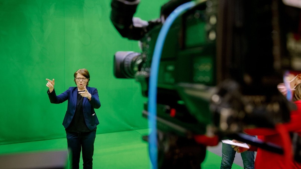 Eine Gebärdendolmetscherin übersetzt in einem TV-Studio in Gebärdensprache.