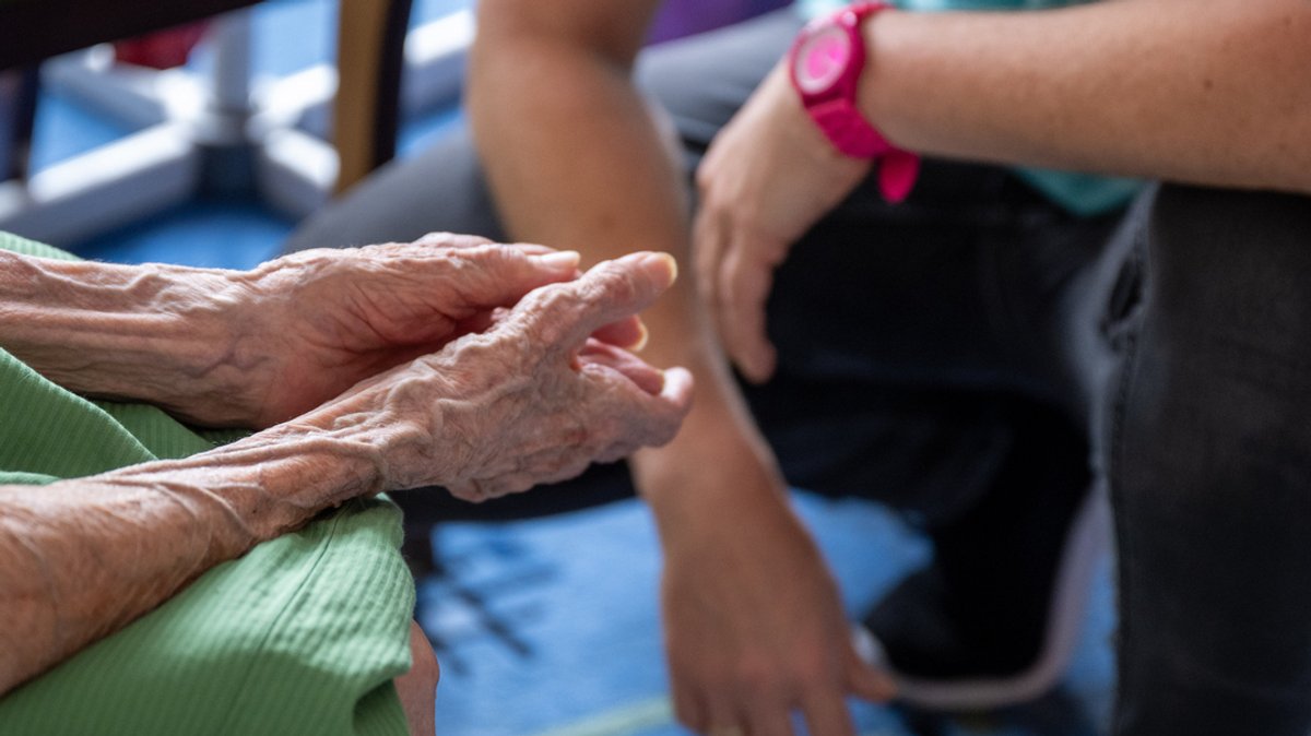 Eine Pflegerin spricht bei einem Hausbesuch mit ihrer pflegebedürftigen Patientin.