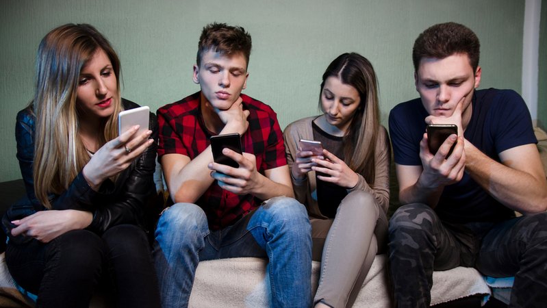 Vier junge Erwachsene schauen in ihre Smartphones. | Bild: stock.adobe.com/phoenix021 Vier junge Erwachsene schauen in ihre Smartphones.