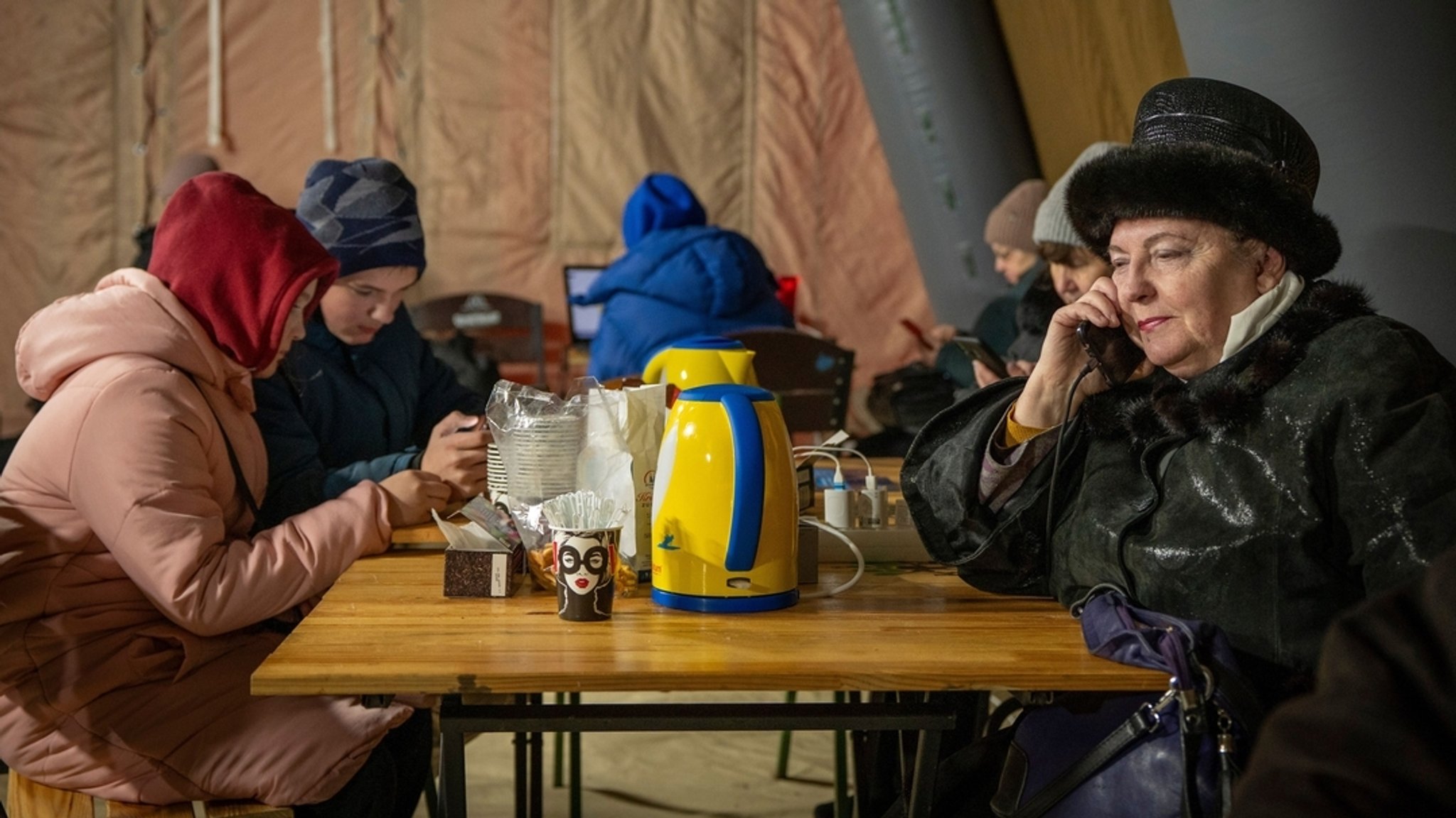 13.01.2026, Ukraine, Kiew: Menschen wärmen sich und laden ihre Akkus in einem Zelt auf, das der Rettungsdienst nach den russischen Luftangriffen auf den ukrainischen Energiesektor aufgestellt hat. Ein Teil der Bewohner der Stadt sind mitten im Winter ohne Strom, Wasser und Heizung. | Bild: dpa-Bildfunk/Danyil Bashakov 13.01.2026, Ukraine, Kiew: Menschen wärmen sich und laden ihre Akkus in einem Zelt auf, das der Rettungsdienst nach den russischen Luftangriffen auf den ukrainischen Energiesektor aufgestellt hat. Ein Teil der Bewohner der Stadt sind mitten im Winter ohne Strom, Wasser und Heizung.