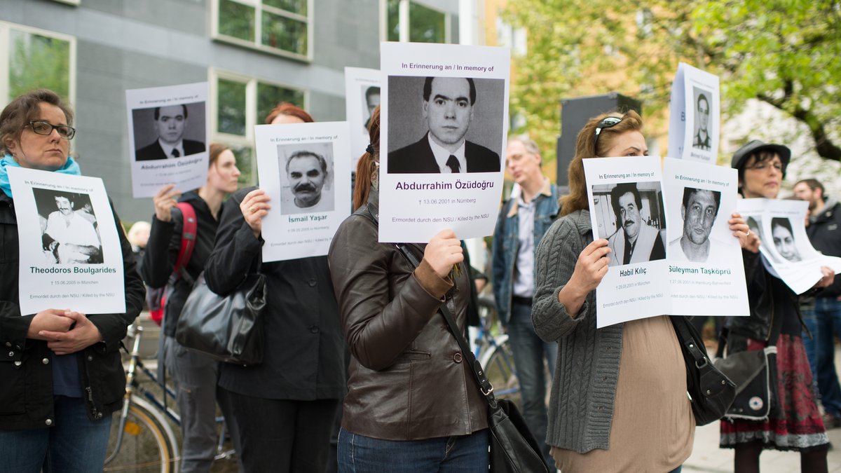 Demonstranten halten bei Prozessbeginn Fotos der NSU-Opfer hoch