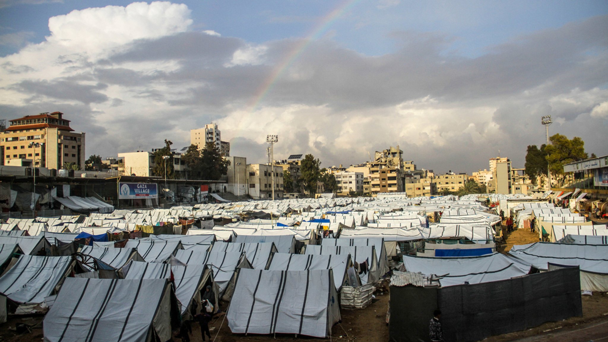 Ein Regenbogen steht über einer Zeltstadt in Gaza. 