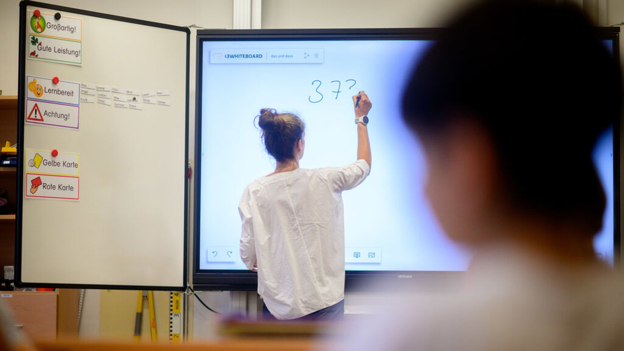 ARCHIV - 17.08.2023, Eine Lehrerin schreibt eine Mathematikaufgabe auf eine digitale Schultafel im Klassenraum einer 4. Klasse einer Grundschule in der Region Hannover. (zu dpa «Philologenchef: «Lehrkräfte ergreifen die Flucht»») Foto: Julian Stratenschulte/dpa +++ dpa-Bildfunk +++