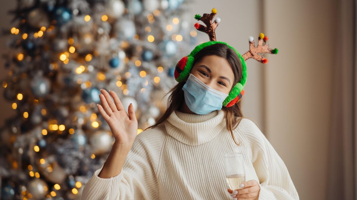 Junge Frau mit Schutzmaske vor Weihnachtsbaum