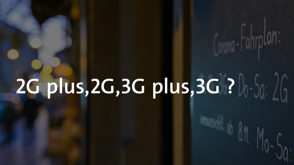 Auf einem Hintergrund mit einer Tafel, auf der Corona-Fahrplan steht, steht "2G plus, 2G, 3G plus, 3G?"