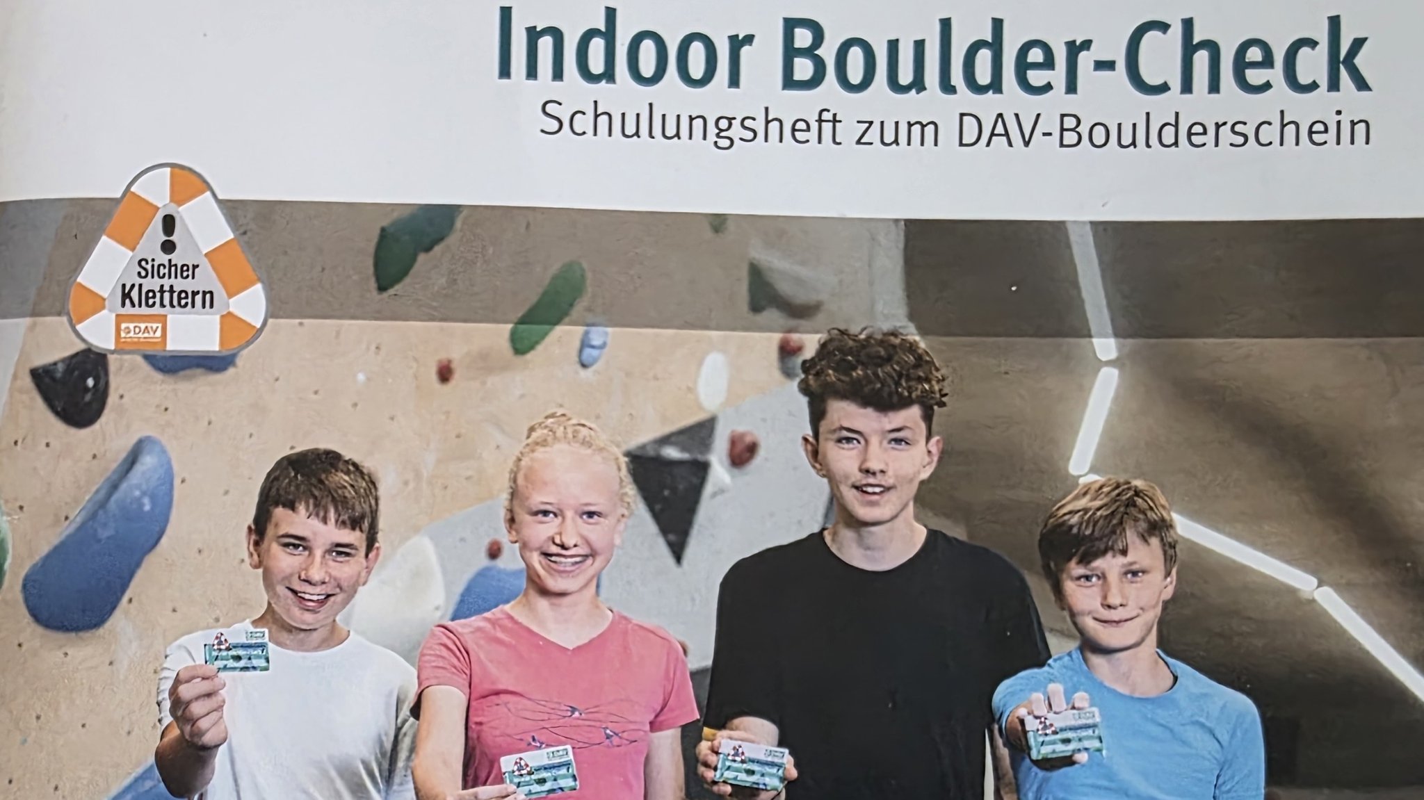 Vier junge Boulderer zeigen ihren DAV-Boulderschein vor.