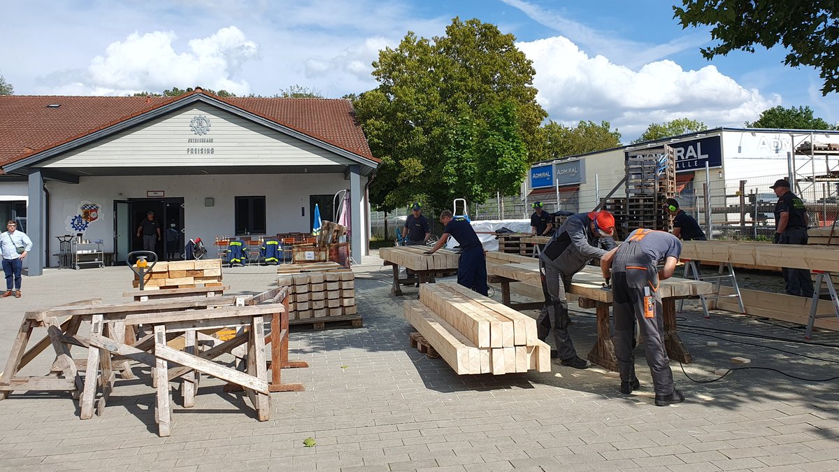 Zu sehen sind THW Mitarbeiter und Helfer in Freising, die Holz bearbeiten, das nach Slowenien gebracht werden soll