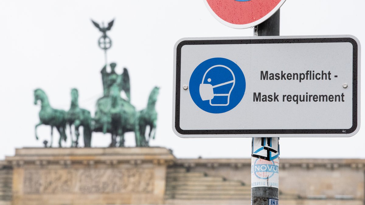 Am Pariser Platz vor dem Brandenburger Tor weist ein Hinweisschild auf die Maskenpflicht hin.