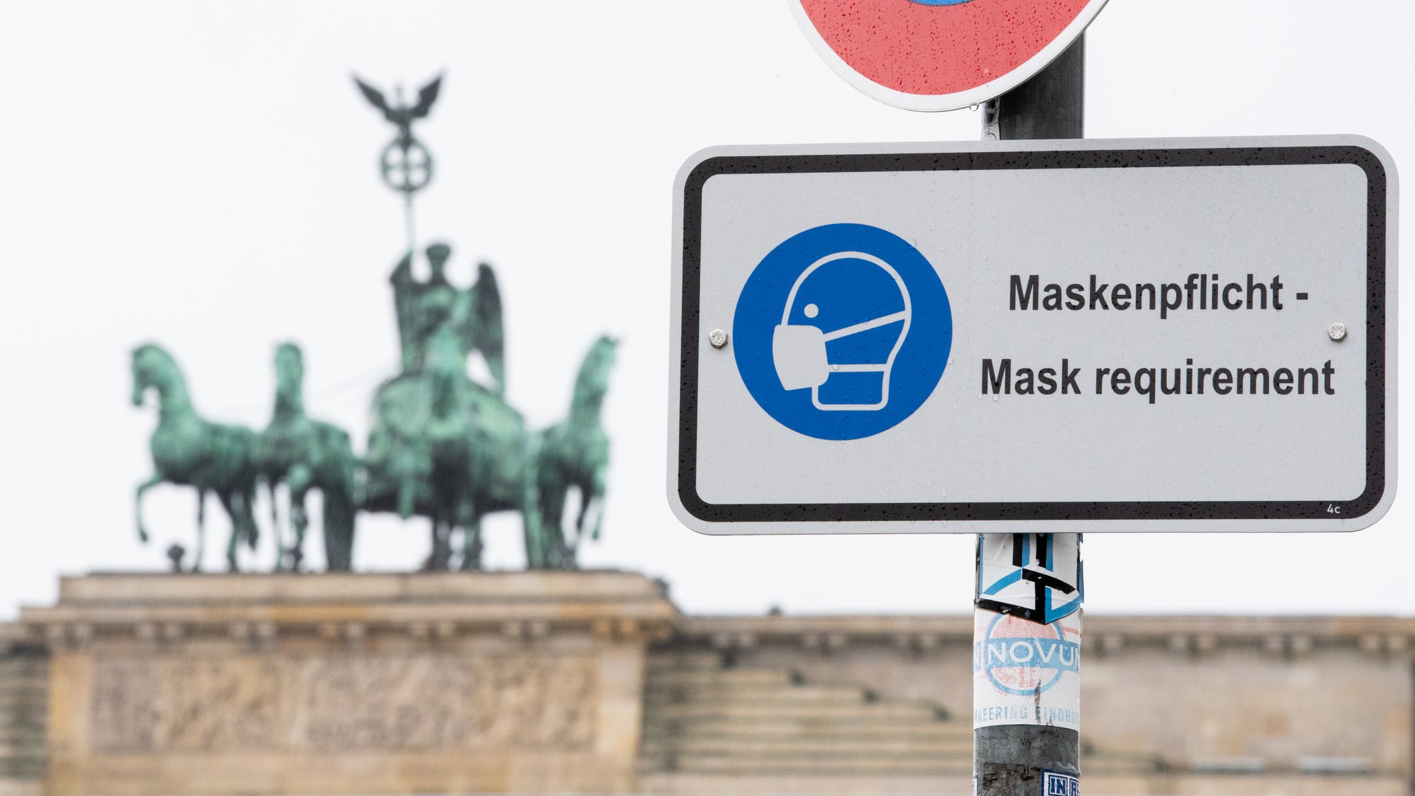 Am Pariser Platz vor dem Brandenburger Tor weist ein Hinweisschild auf die Maskenpflicht hin.