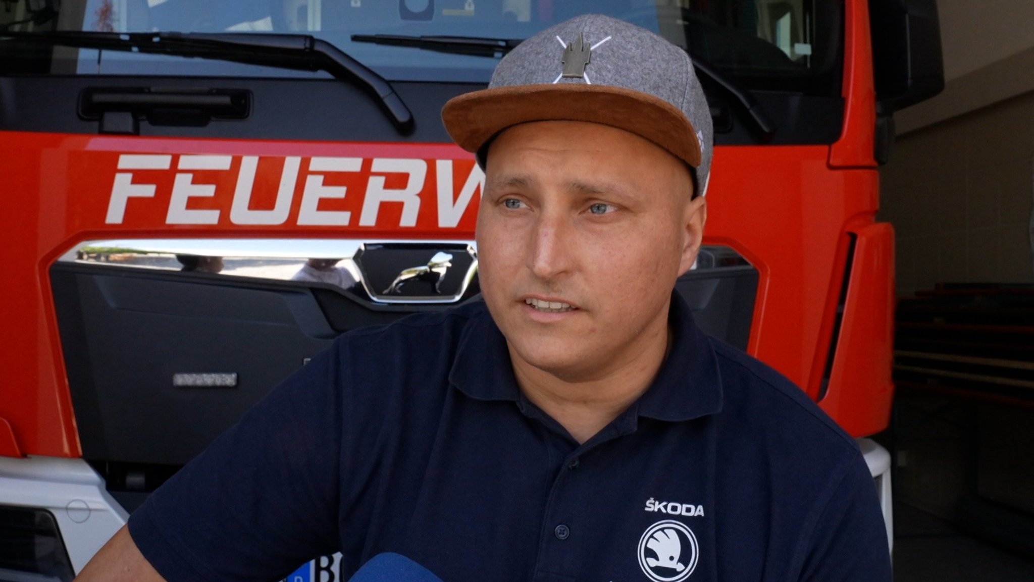 Der 36-jährige Stefan Kronfeldner sitzt vor einem Feuerwehrauto.