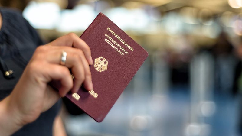 Eine Frau hält einen deutschen Reisepass in der Hand.