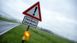 Ein Warnschild mit der Aufschrift "Fahrbahn überflutet". | Bild:picture alliance/dpa | Pia Bayer