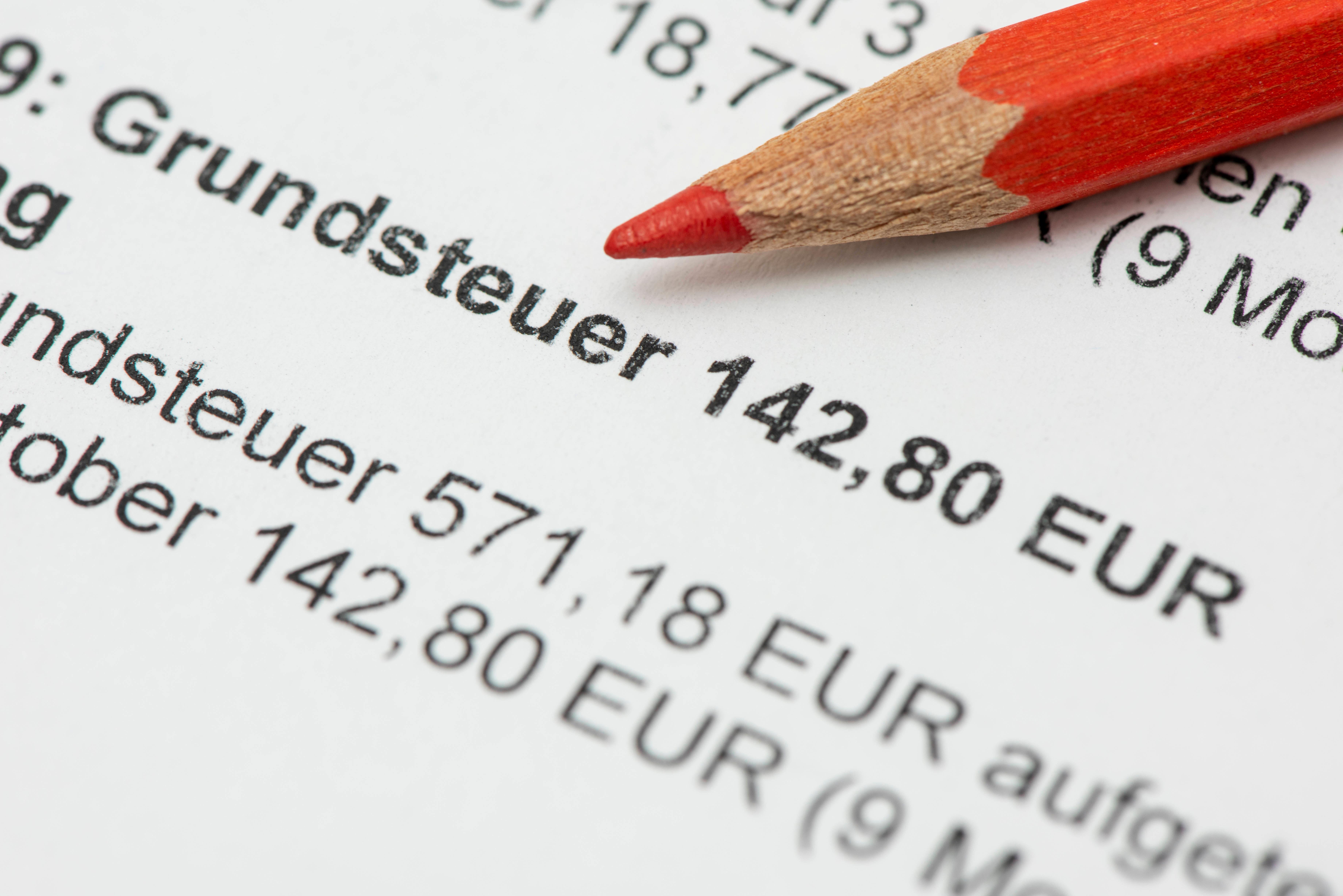 (Symbolbild) Ein Rotstift liegt auf einer Abrechnung für die Grundsteuer. 