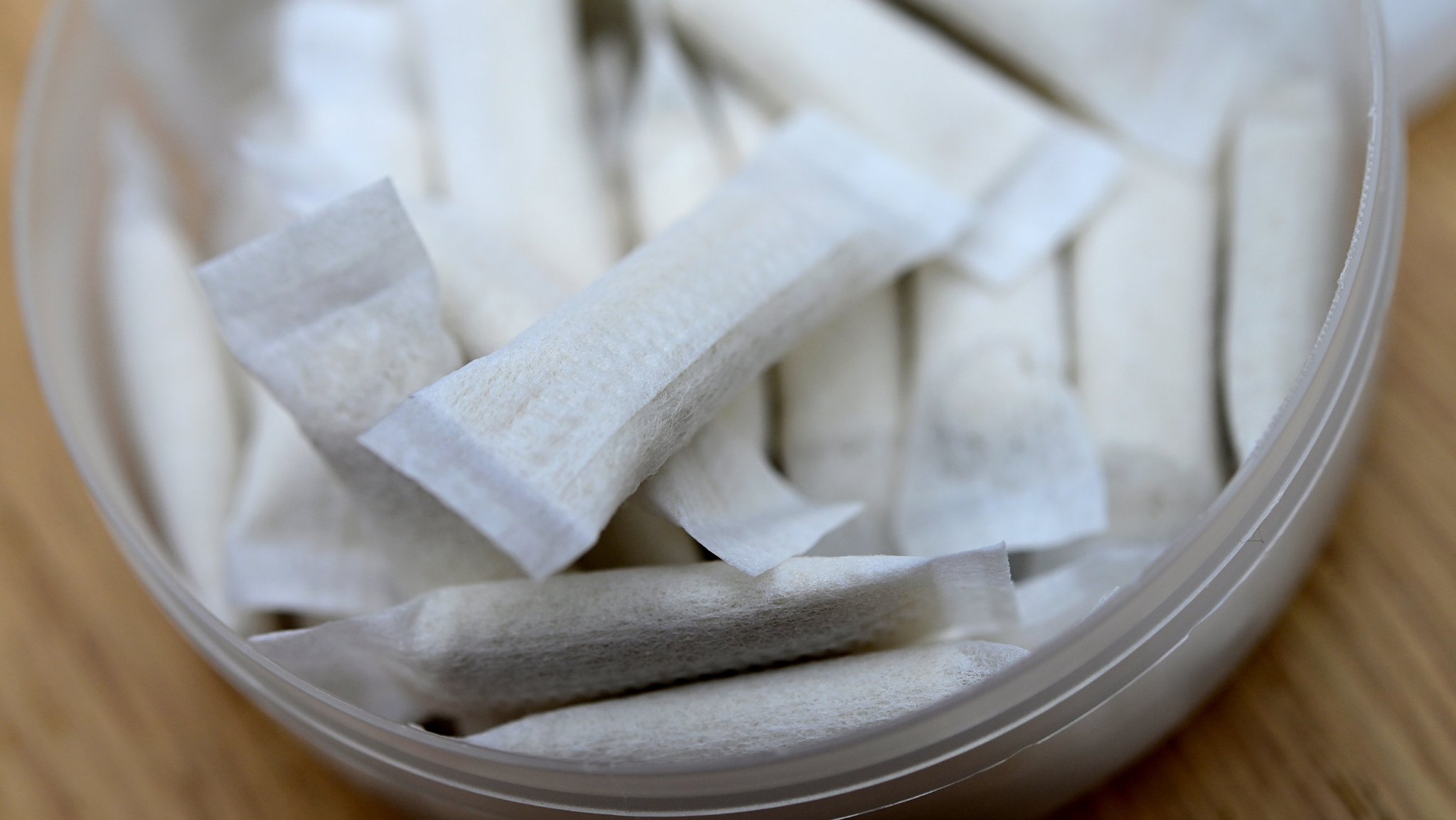 Eine Dose mit Nikotinbeuteln auf einem Tisch. Nikotinbeutel enthalten keinen Tabak und sind auch als Pouches bekannt.