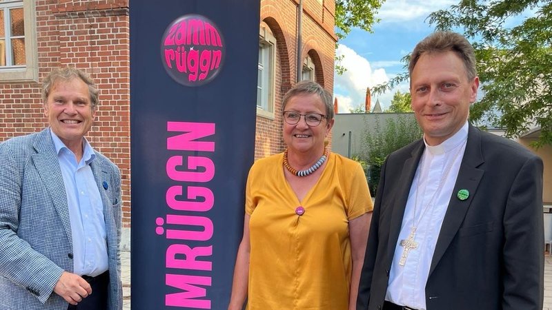 Drei Menschen stehen an einem Rollup von "Zammrüggn" | Bild: Katholische Stadtkirche Nürnberg Drei Menschen stehen an einem Rollup von "Zammrüggn"