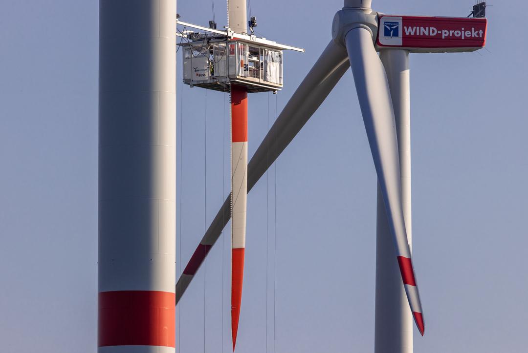 Spezialisten warten von einer Gondel aus ein Rotorblatt 