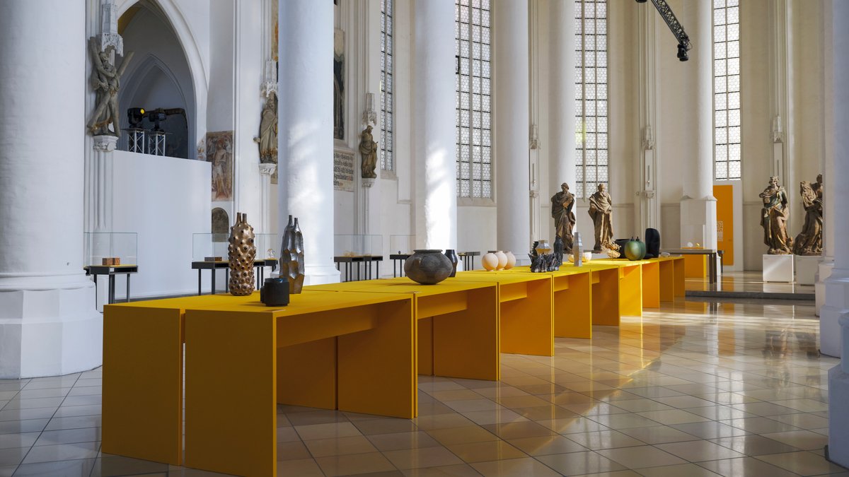 Blick in die Heiliggeistkirche in Landshut mit den Ausstellungsobjekten auf safrangelben Tischen