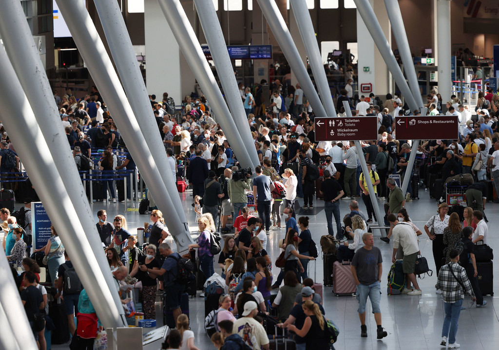 25.06.2022, Nordrhein-Westfalen, Düsseldorf: Passagiere stehen im Flughafen Düsseldorf in Schlangen und warten auf ihre Abfertigungen.