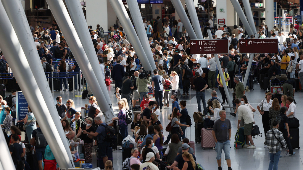 25.06.2022, Nordrhein-Westfalen, Düsseldorf: Passagiere stehen im Flughafen Düsseldorf in Schlangen und warten auf ihre Abfertigungen.