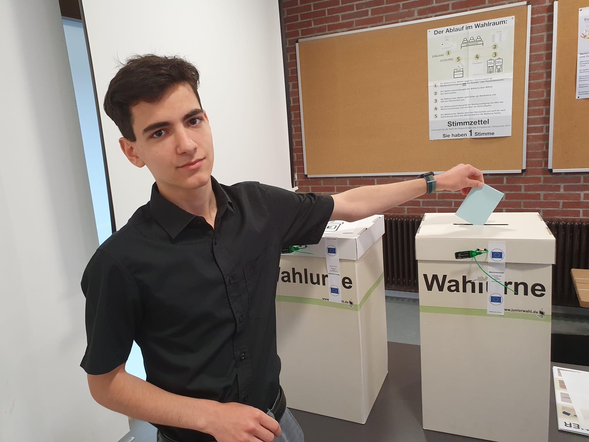 Ein Schüler wirft seinen Stimmzettel in die Wahlurne ein.