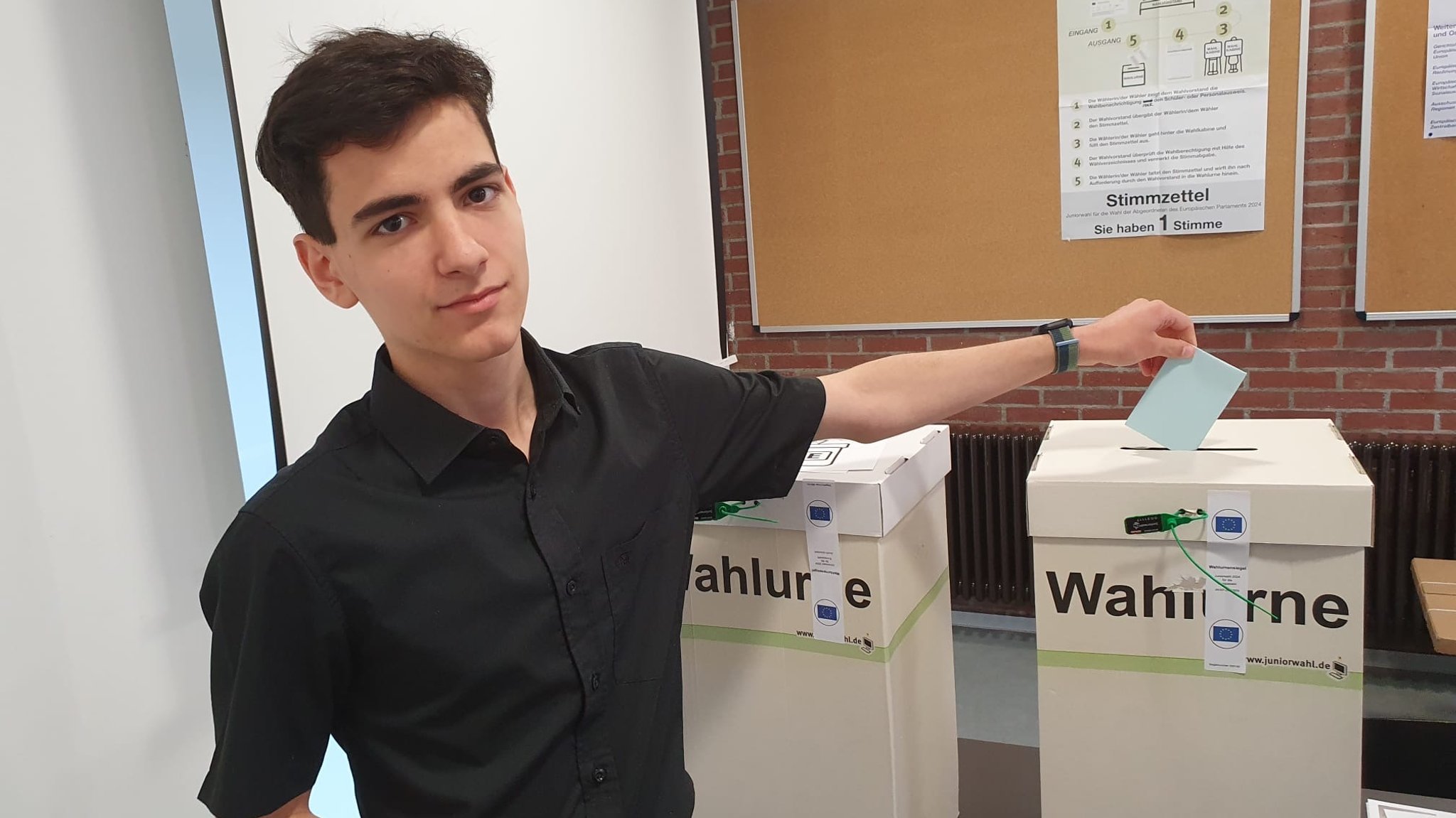 Ein Schüler wirft seinen Stimmzettel in die Wahlurne ein.