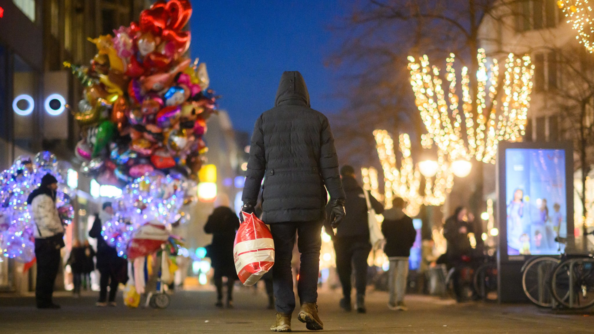 Ein Passant läuft mit einer Einkaufstasch durch die Innenstadt.