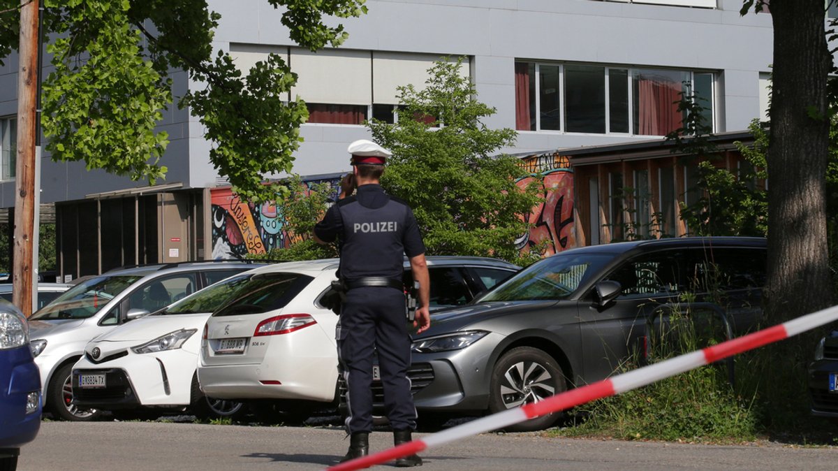 Ein Polizeibeamter telefoniert vor dem Grazer Schulgebäude, wo ein 21-Jähriger am Dienstag Amok lief.