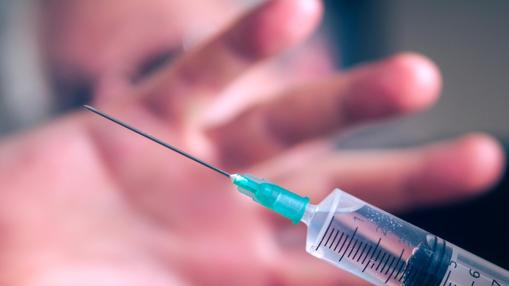 Hand in Abwehrhaltung gegen eine Spritze oder Impfung