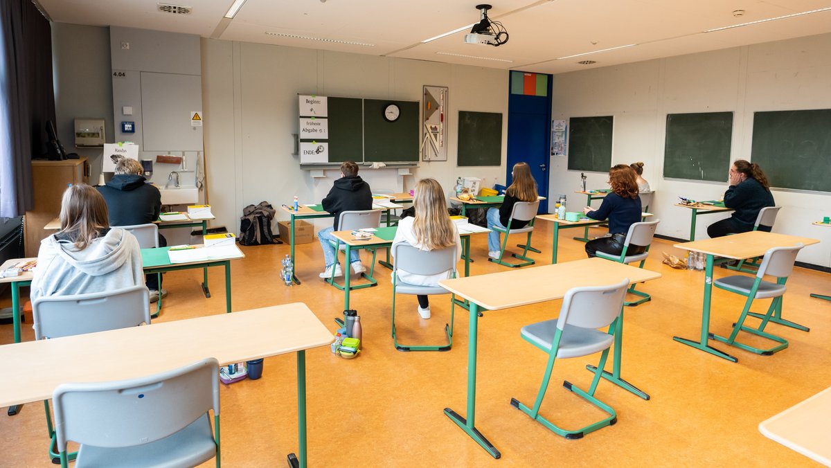 Schülerinnen und Schüler sitzen vor Beginn der schriftlichen Abiturprüfung in einem Klassenzimmer.