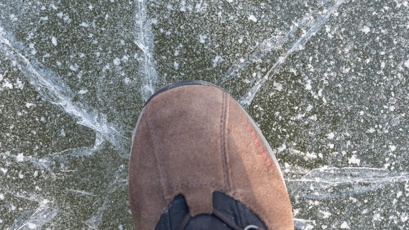 Eine Schuhspitze bringt eine Eisfläche zum knacken