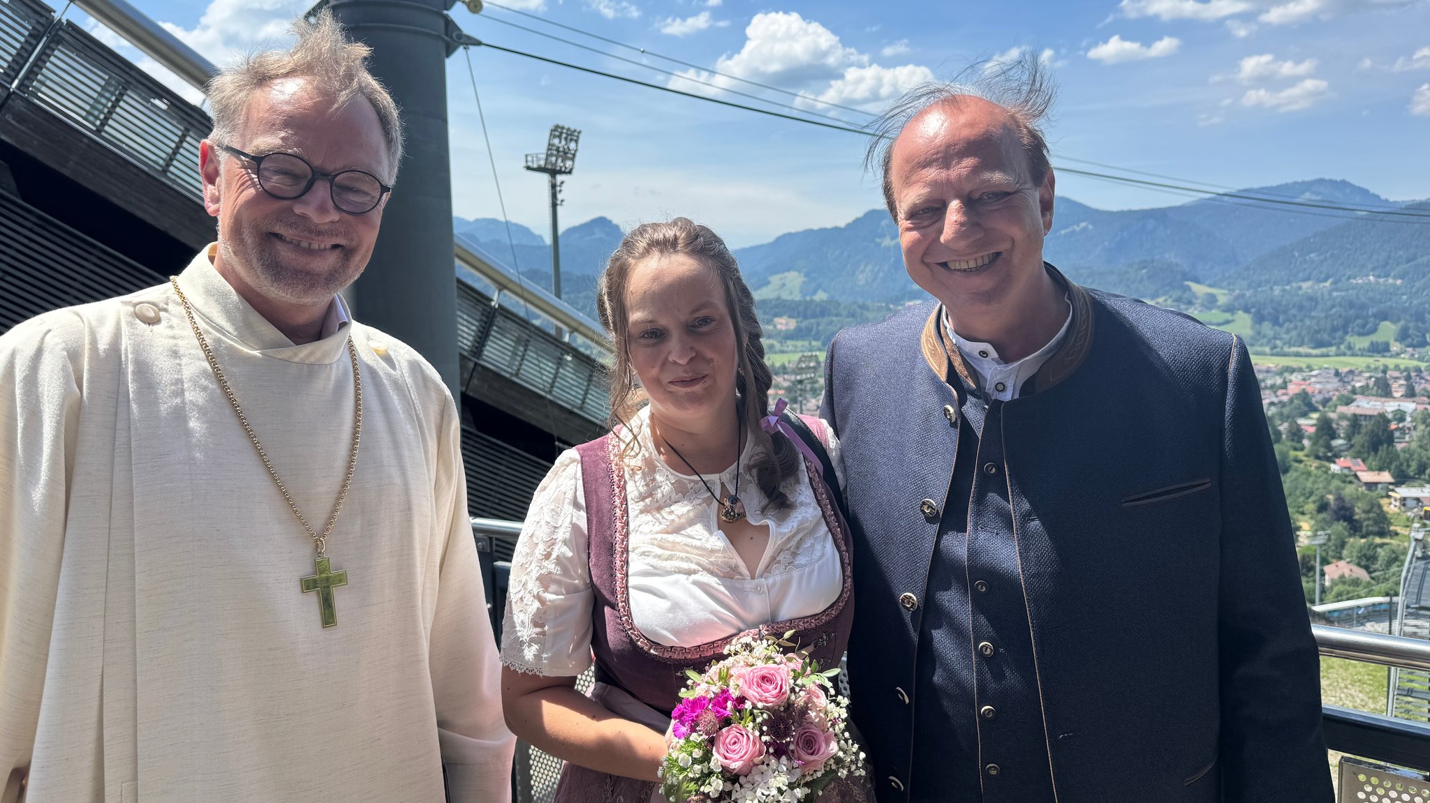 Sie haben sich auf der Skisprungschanze in Oberstdorf das Ja-Wort gegeben: Sandra und Peter Abbenhaus mit Regionalbischof Thomas Prieto Peral. | Bild: BR/ Astrid Uhr Sie haben sich auf der Skisprungschanze in Oberstdorf das Ja-Wort gegeben: Sandra und Peter Abbenhaus mit Regionalbischof Thomas Prieto Peral.
