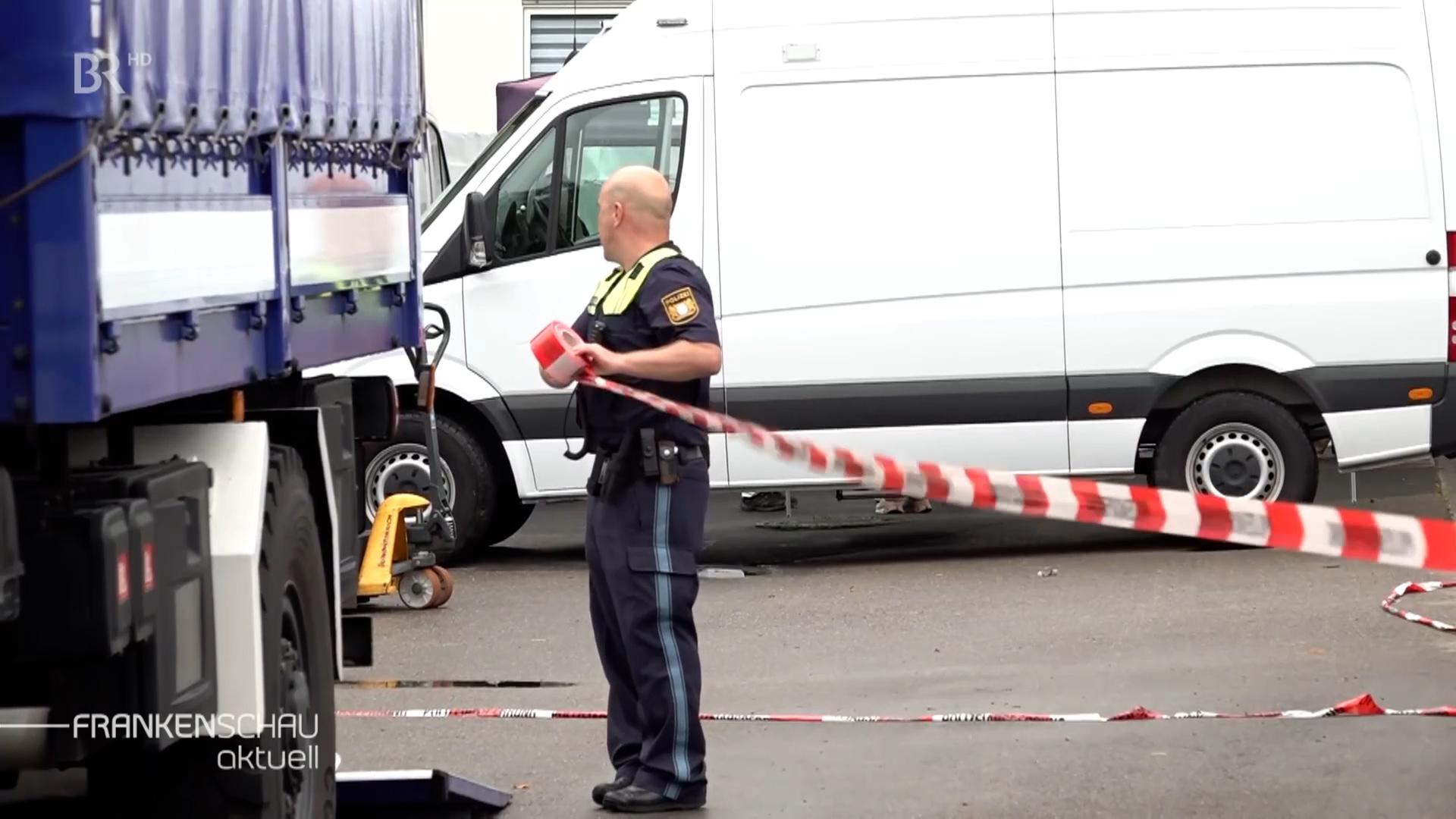 Ein Polizist legt ein Absperrband an.