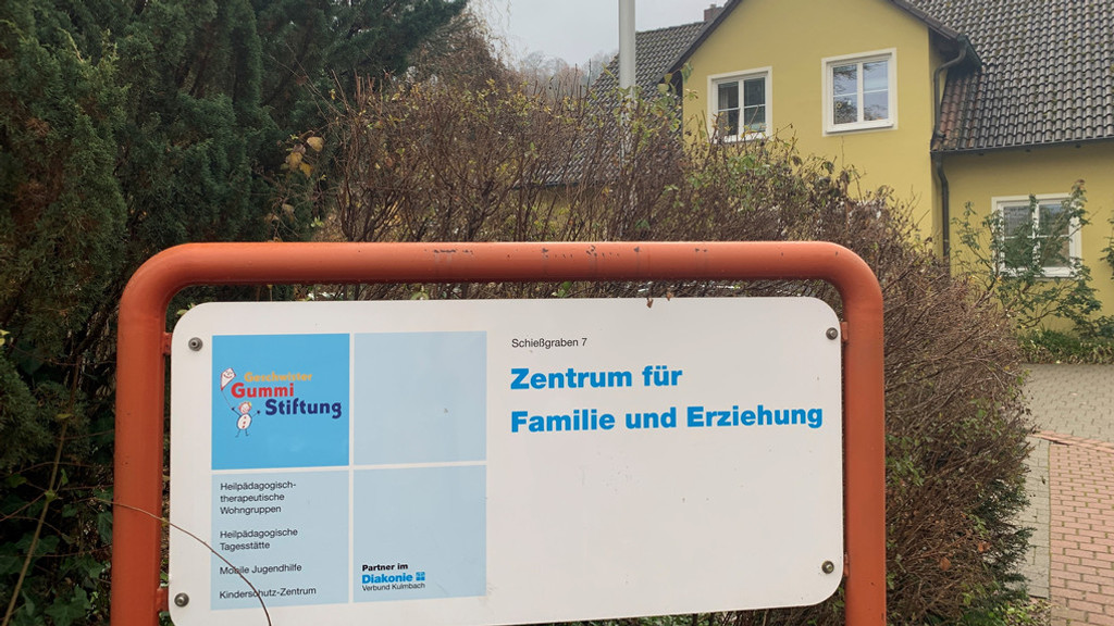 Ein Schild mit der Aufschrift "Zentrum für Familie und Erziehung" vor einem Haus mit gelber Fassade. 