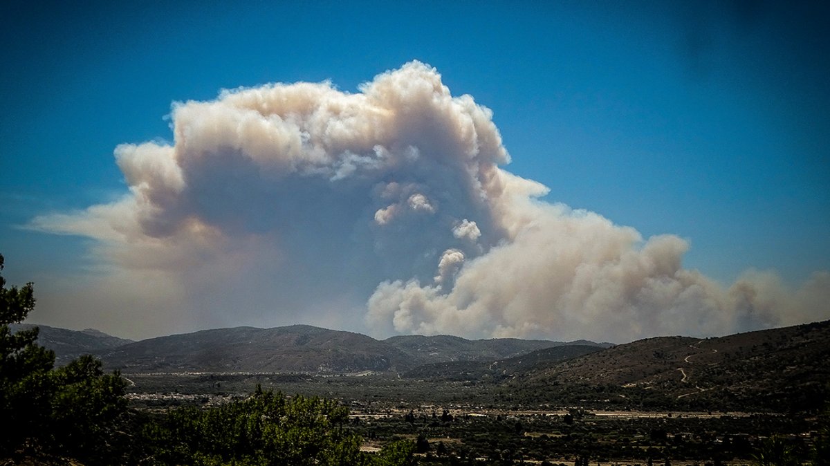 Eine große Rauchwolke eines Waldbrandes schwebt über der griechischen Insel Rhodos. Bei Waldbränden können Urlauber kostenlos zurücktreten.