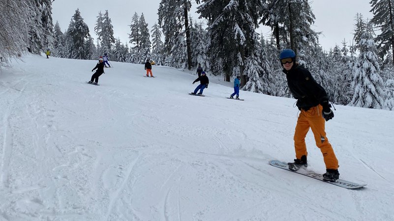 Eine Skipiste mit Ski- und Snowboardfahrern. 
