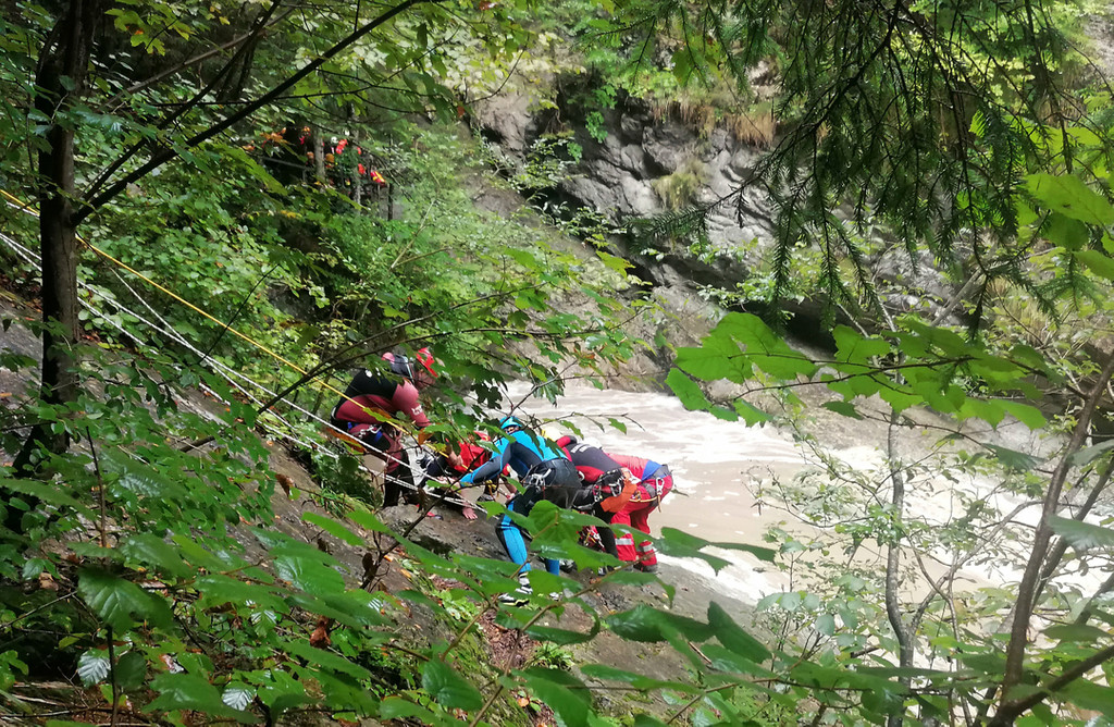 Retter arbeiten an einem Steilhang am Flussufer: Eine Frau wird vermisst, nachdem ihre Gruppe beim sogenannten Canyoning in der Starzlachklamm  von einer Sturzflut überrascht wurde.