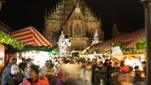 Nürnberger Christkindlesmarkt mit der beleuchteten Westfassade der Frauenkirche im Hintergrund.
| Bild:adobestock